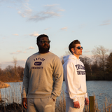 Two men posing with Taylor University apparel on with pond behind them.