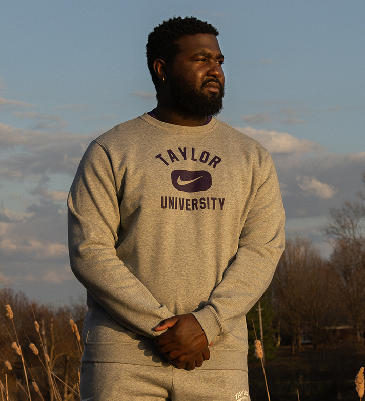 Male standing wearing Taylor University crew neck.